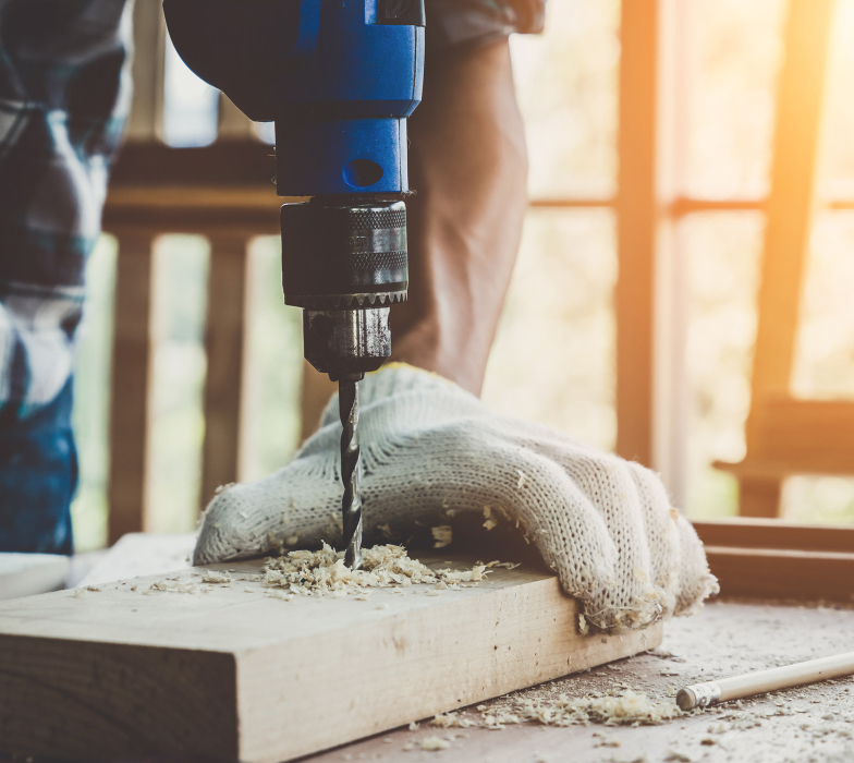 man holding drill on piece of wood